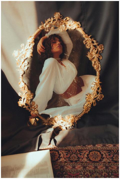 A woman in vintage attire reflected in an ornate g