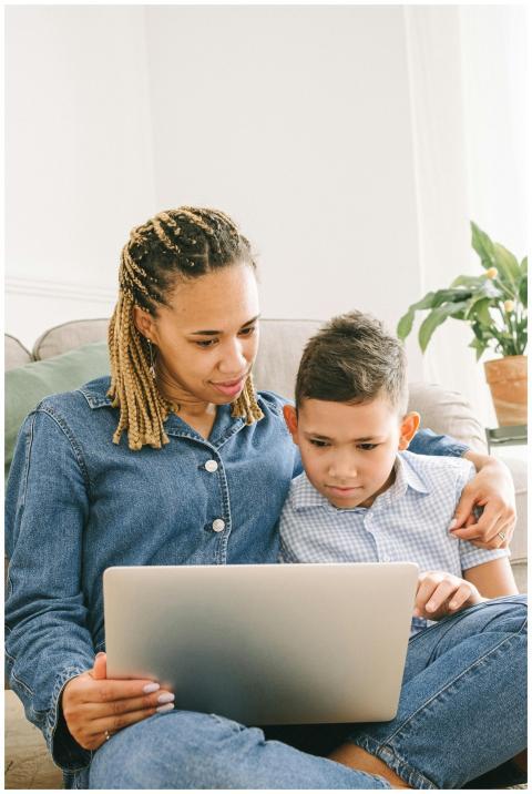 A mother and son using a laptop on the sofa, engag