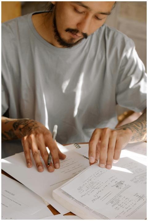 Young adult with tattoos studying diligently with