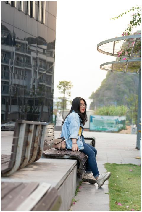 Young woman sitting casually on a bench outdoors w