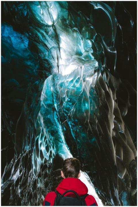 Person exploring a stunning turquoise ice cave in