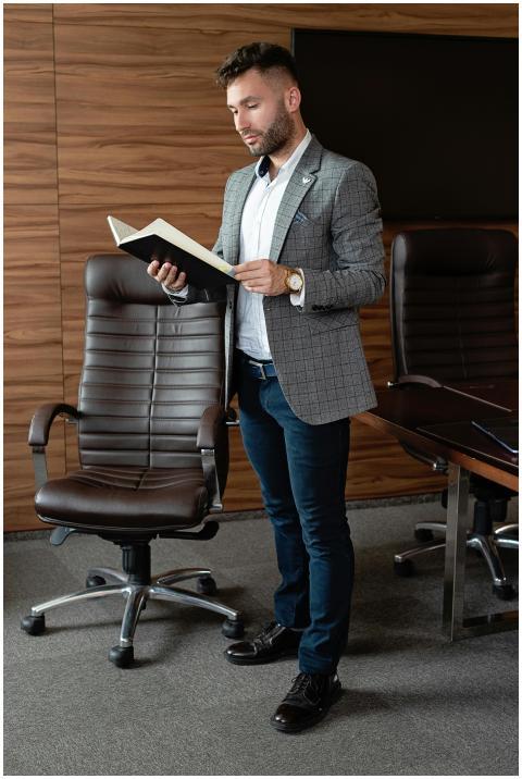 A businessman in a suit reading a book while stand