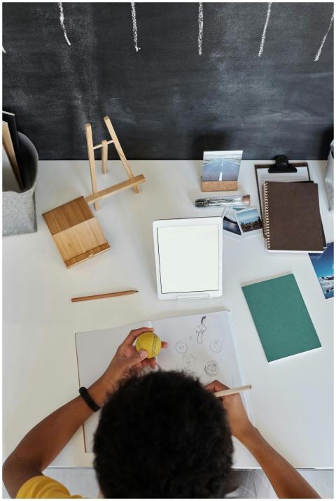 Overhead view of a teenager drawing at a desk with