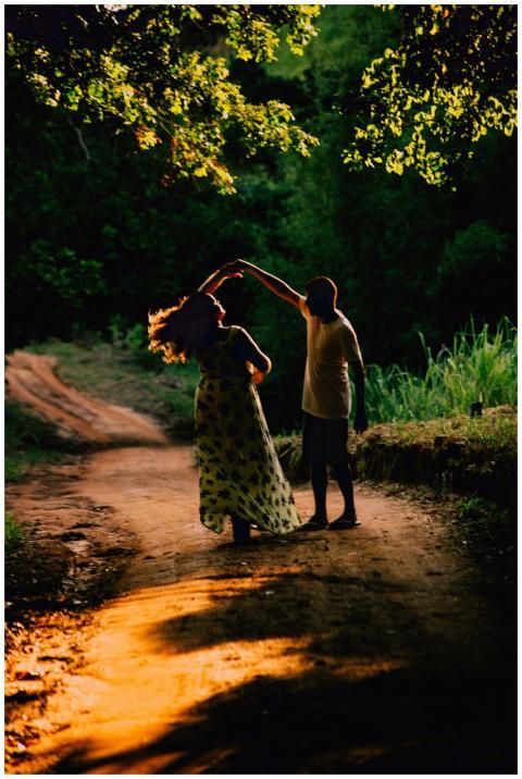 A couple gracefully dances on a sunlit dirt road s