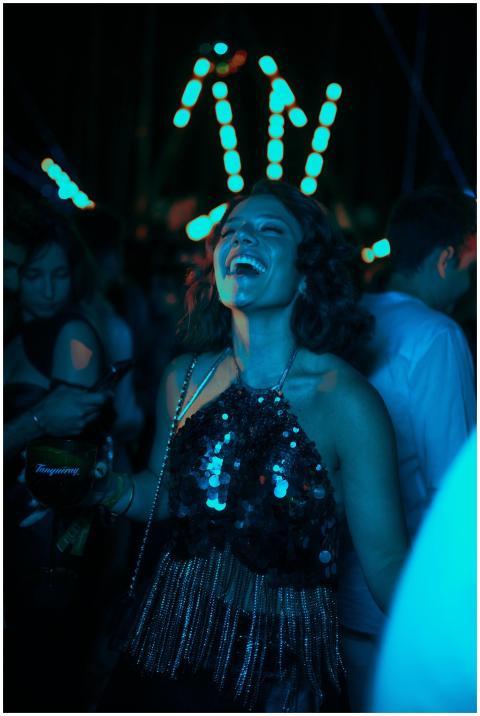Woman in sequined dress laughing and dancing in a