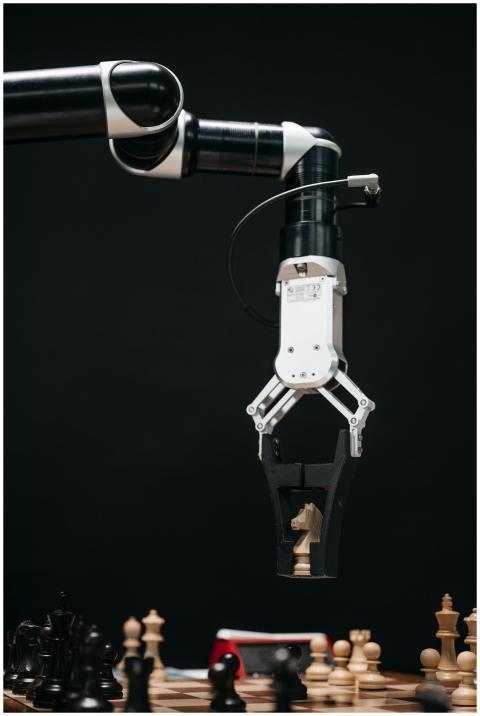 A robotic arm with a pincers holding a knight ches