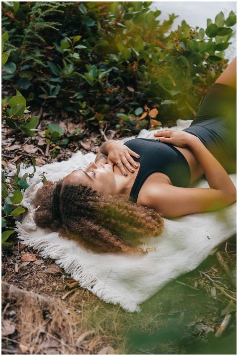 A woman with curly hair meditates on a white towel