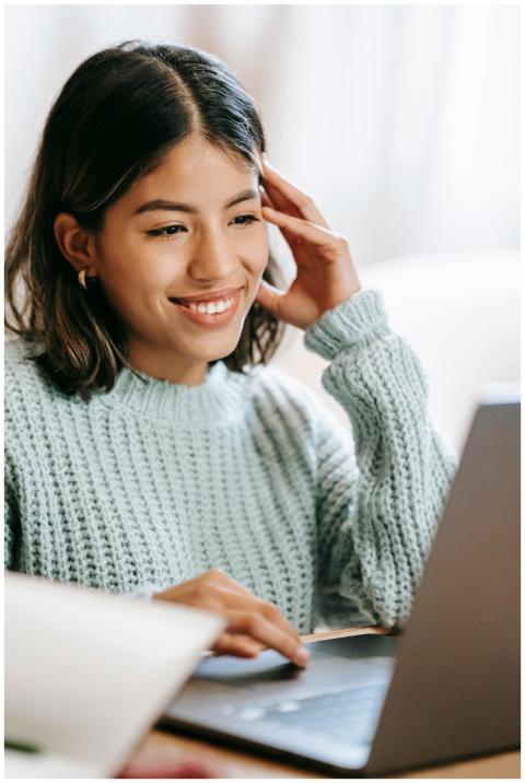 A young woman smiling as she uses a laptop in a co