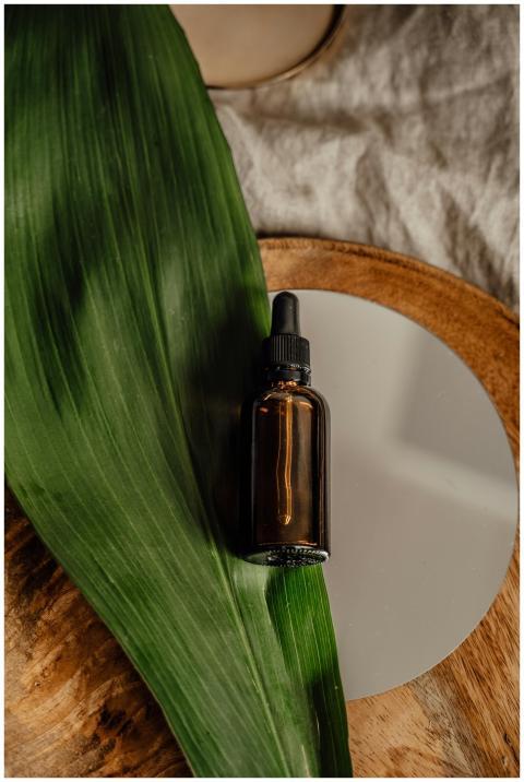 Glass dropper bottle with a green leaf on a wooden