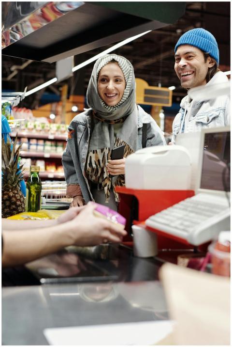 A smiling couple at a supermarket checkout counter