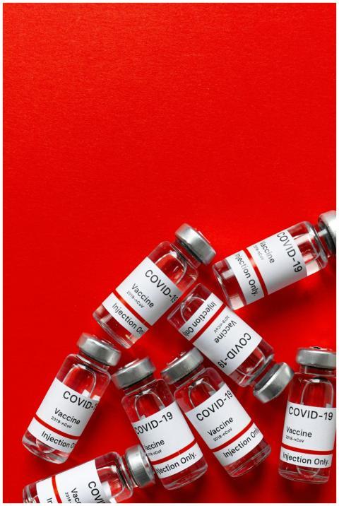 A group of COVID-19 vaccine vials against a vibran