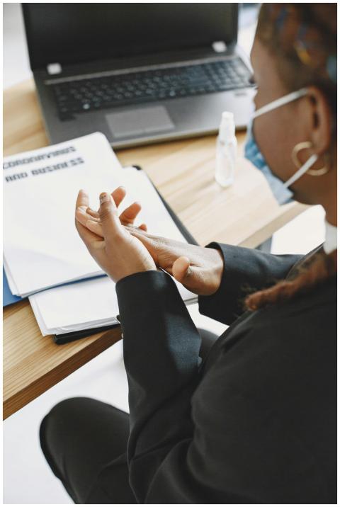 A businesswoman wearing a face mask uses sanitizer
