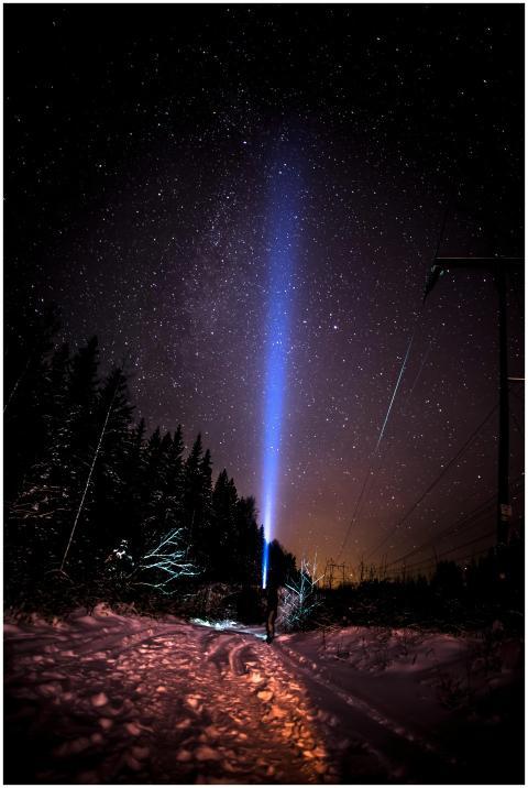 A person with a flashlight in a snowy forest under