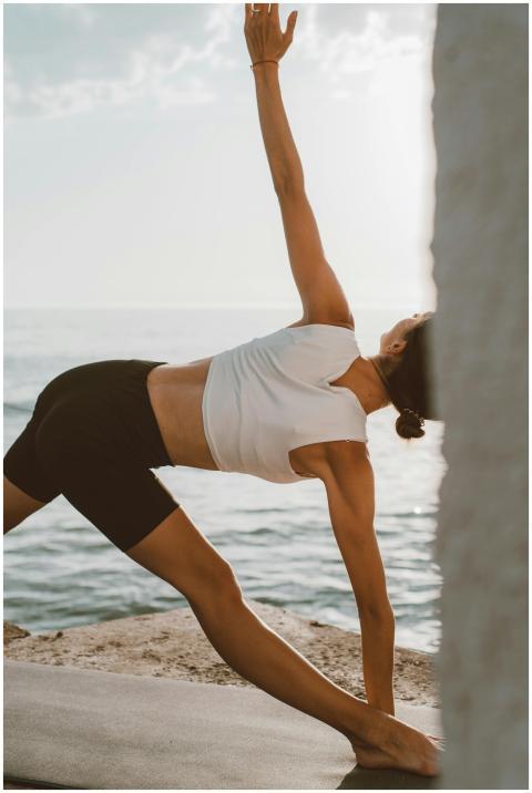 Person practicing yoga outdoors by the sea during