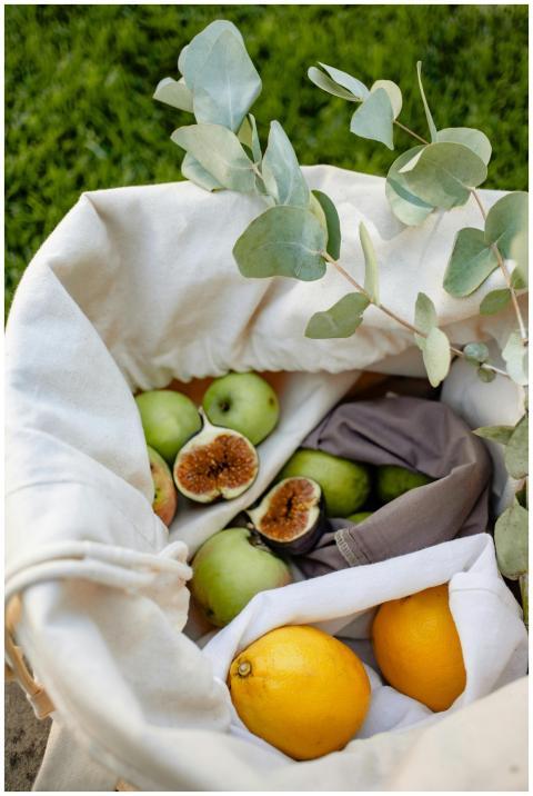 A reusable basket with fresh fruits and eucalyptus
