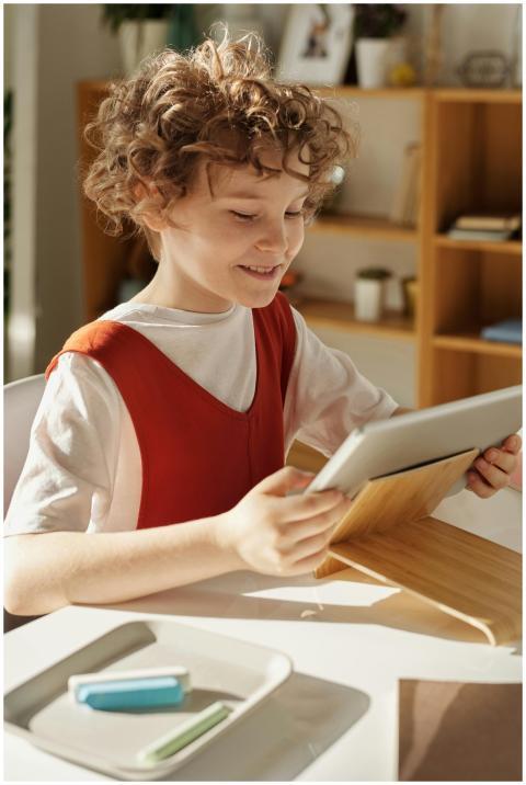 A happy child using a tablet for online education