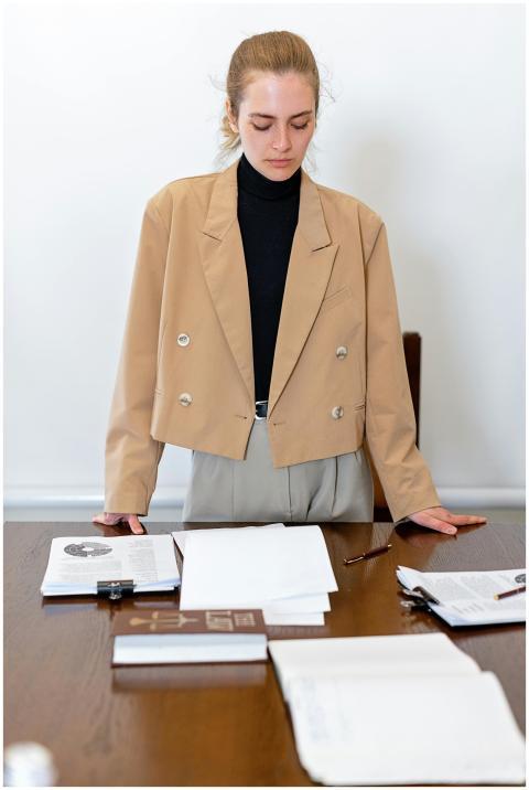 Young businesswoman stands at a desk looking over