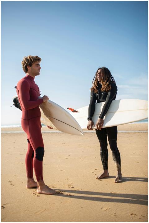 Two surfers in wetsuits with boards on a sunny Por