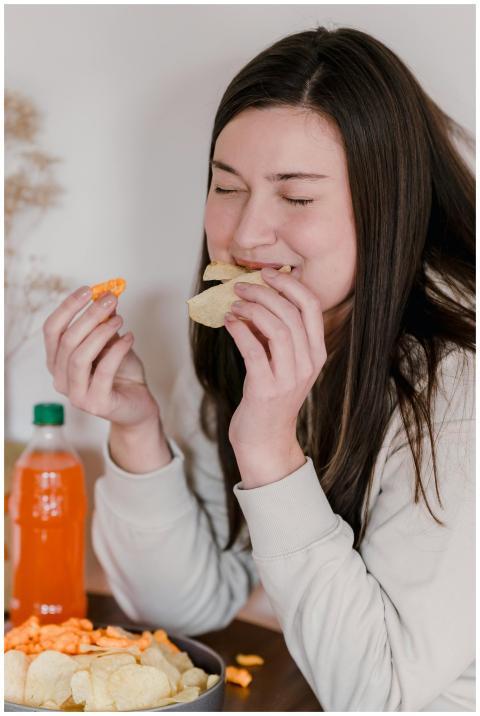 A young woman indulges in chips and soda, savoring