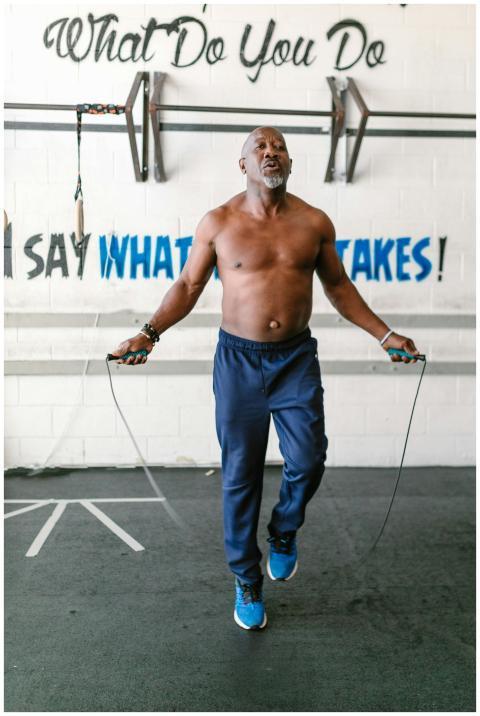 African American man jump roping in gym, promoting