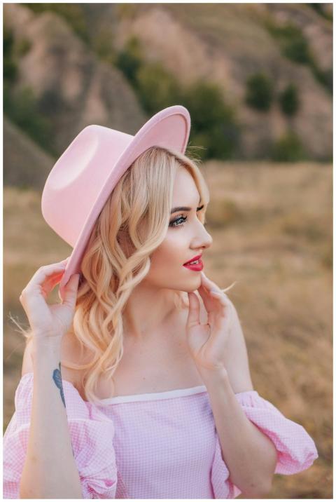 Stylish blonde woman in pink outfit and hat posing