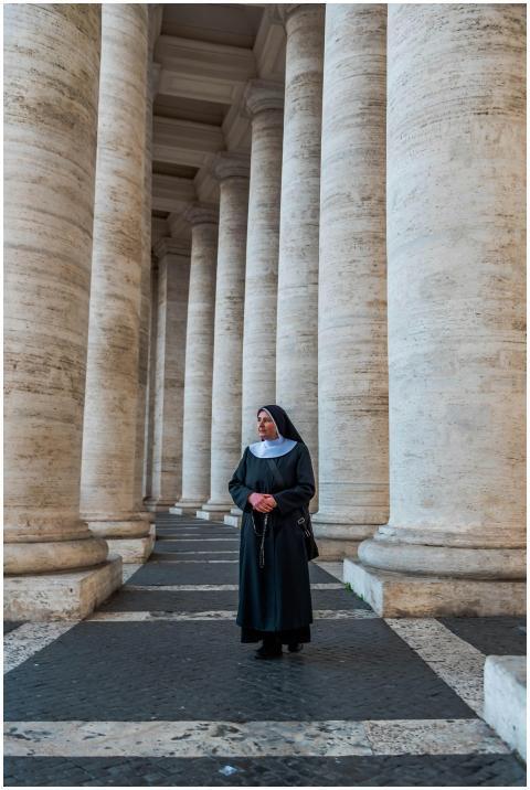 A nun walks through the iconic colonnade of St. Pe