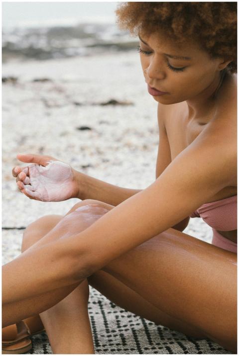 A woman applies sunscreen at the beach, embracing