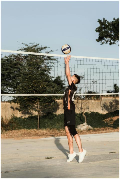 Young male athlete in a black uniform jumping to h