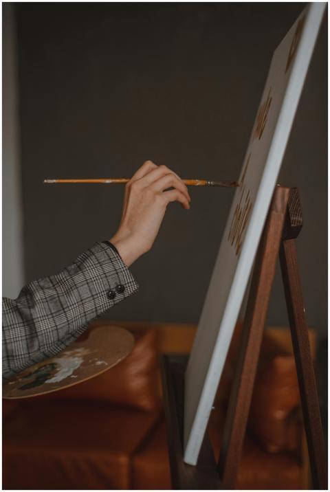 Close-up of an artist's hand painting on canvas us