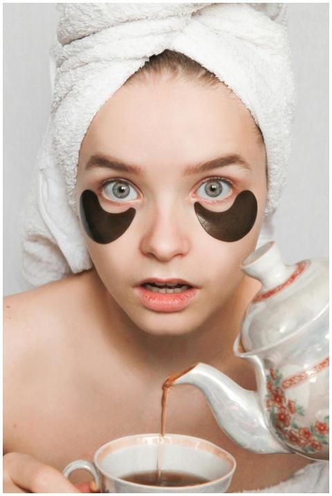 Woman with towel and eye patches pours tea, embody