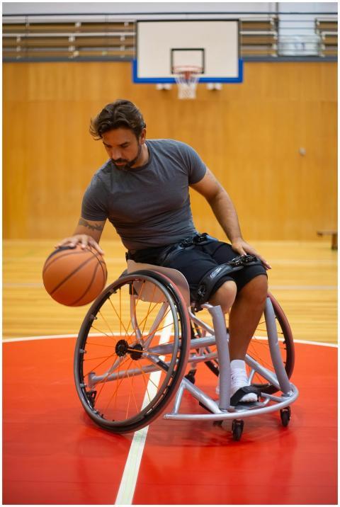 Man in a wheelchair playing basketball indoors, fo