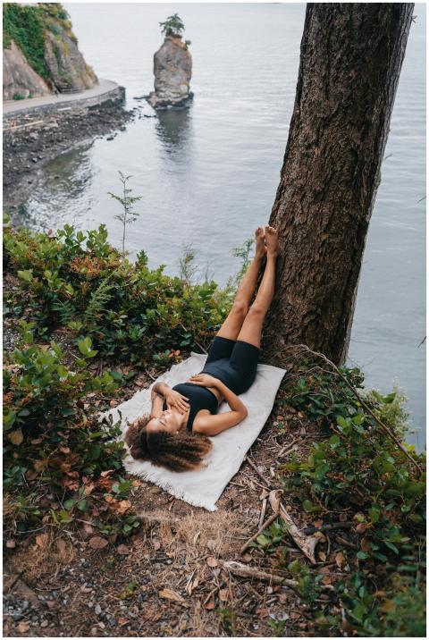 A woman in activewear relaxes by the water's edge