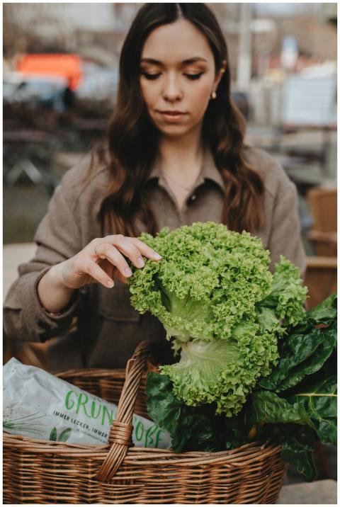 A woman explores fresh green vegetables in a wicke