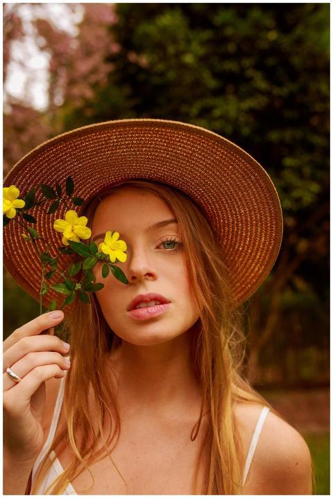 A woman wearing a straw hat holding yellow flowers