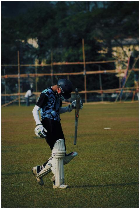 A cricketer in sportswear walking on a cricket fie