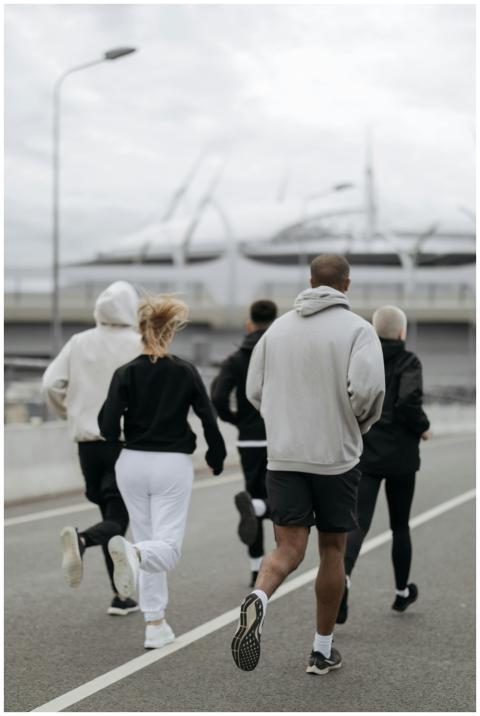 Five adults jogging outdoors in an urban area, pro
