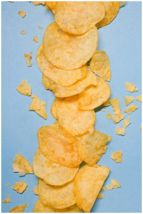 Top view of golden potato crisps placed on blue ba