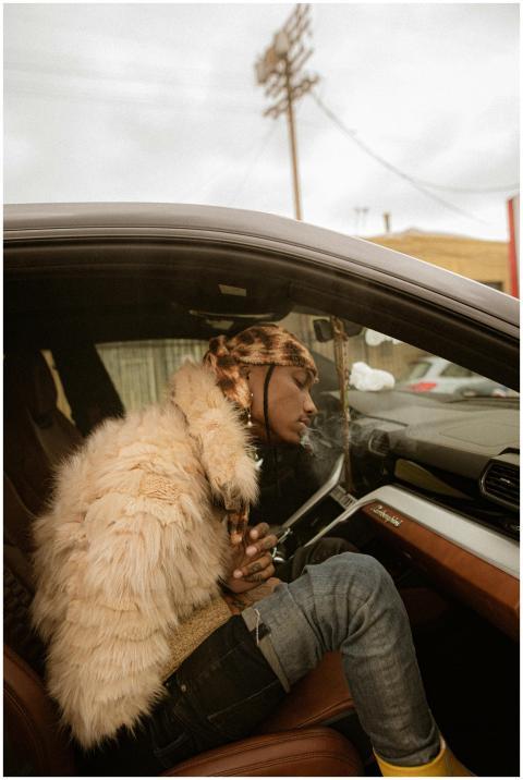 Man in a fur jacket sitting in a luxury car, smoki