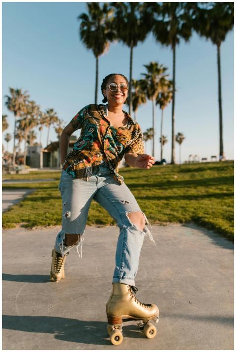 Happy woman in ripped jeans roller skating outdoor