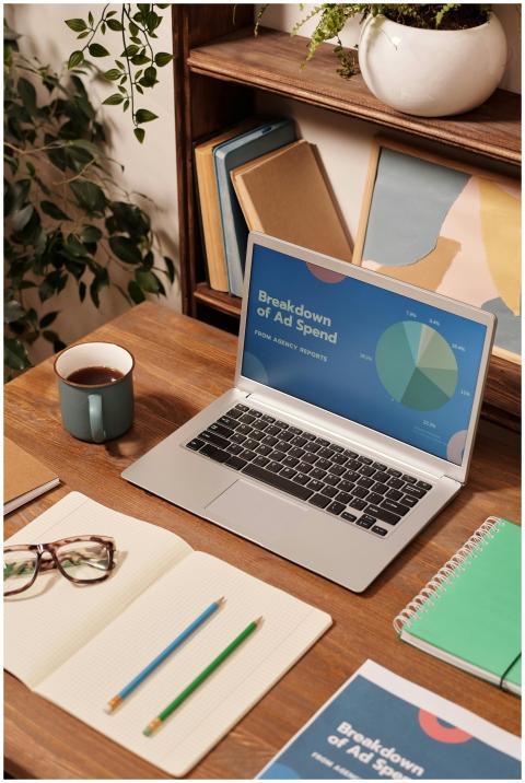 Laptop displaying ad spend data on a wooden desk w