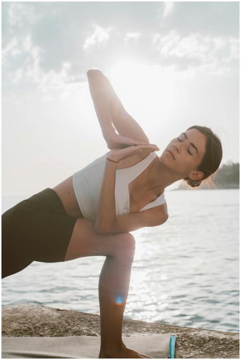 A woman in activewear practicing yoga near the sea