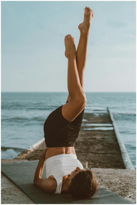 A woman in sports attire performs yoga on a mat by