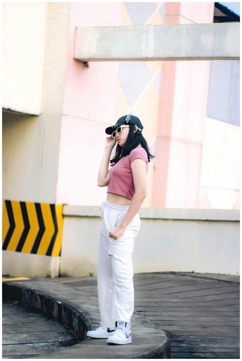 Fashionable woman in cap and sunglasses posing out
