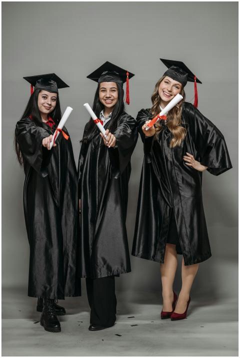 Three women in graduation gowns celebrating with d