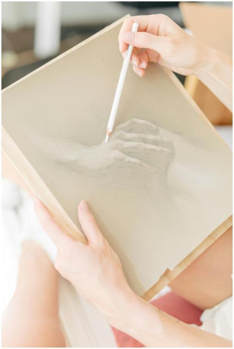 Close-up of hands sketching a hand on paper, captu