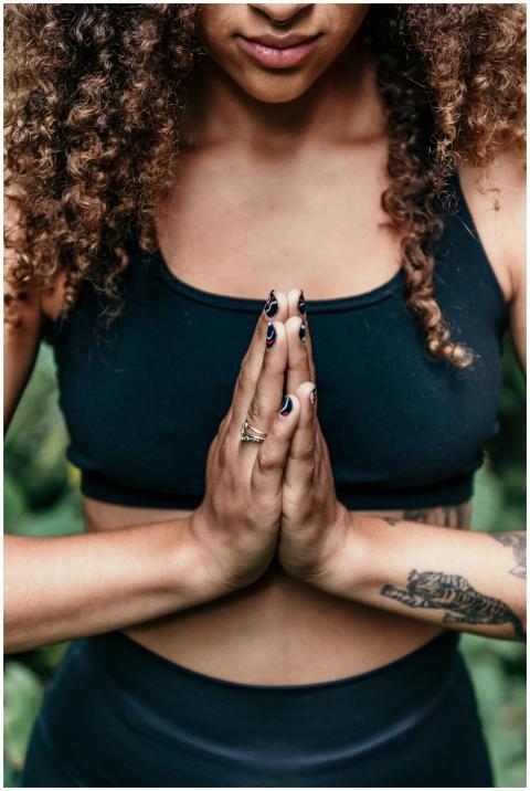 A woman meditating with hands together, wearing a