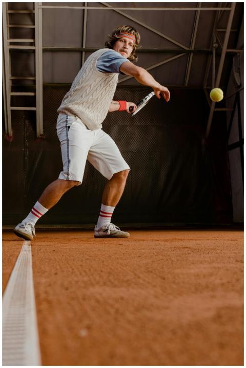 A focused tennis player hits a ball on an indoor c