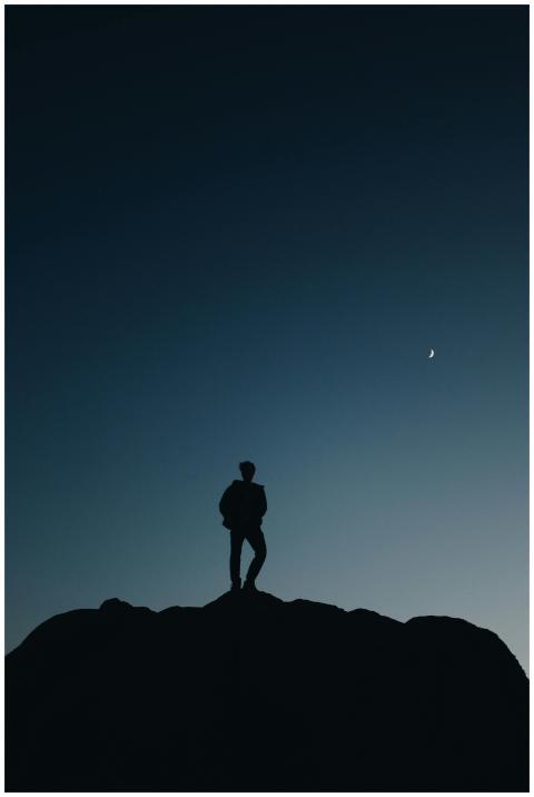 Silhouette of a person standing on a hilltop under