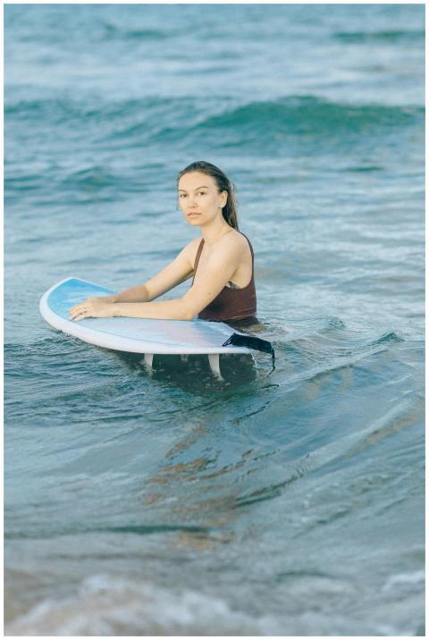 A woman with a surfboard enjoys a peaceful moment
