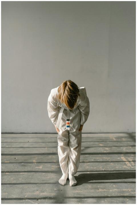 A child bows in a martial arts gi, practicing resp